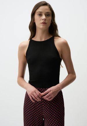 Top in cotone nero a coste con collo alto, abbinato a leggins rossi e neri con un motivo a diamante. Tessuto morbido, taglio aderente.