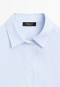 Camicia a righe blu chiaro con colletto classico e due bottoni bianchi, con un'etichetta che recita "Massimo Dutti, Made in Morocco."