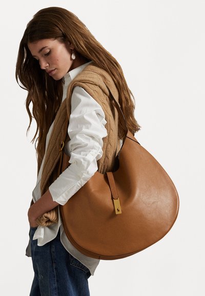 Kavos odinė petneša, turinti kreivą formą, auksinius akcentus ir viršutinę rankeną. Strukturinis paviršius su minkštu apdailu.