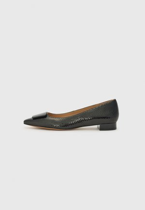 Scarpa piatta nera con punta affusolata, motivo testurizzato a rettile e un accento di fiocco nero lucido sulla parte anteriore. Tacco basso e spesso.