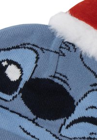 Cappello di maglia blu con un volto di un personaggio dei cartoni animati in evidenza, con accenti in bianco e nero. Parte superiore in tessuto rosso con bordo in pelliccia bianca.