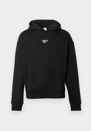 Zwarte hoodie van zacht katoen, met een voorste kangoeroezak, een capuchon met trekkoord en een wit Reebok-logo op de borst. Standaard pasvorm.