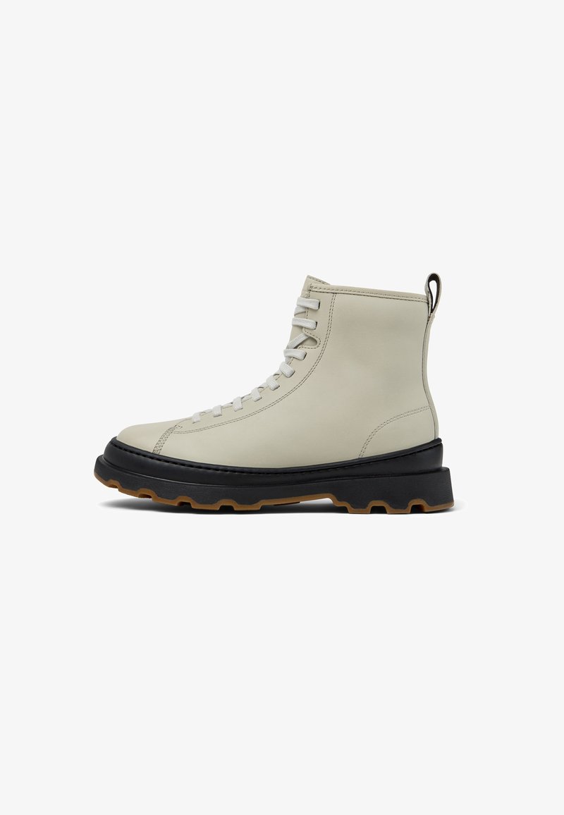Beige leather ankle boots with round toe, raised black sole, and gray laces. Features a pull tab for easy wear and a rugged tread pattern.