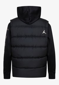Gilet rembourré noir avec capuche, doté de poignets élastiques et d'un petit logo blanc sur la poitrine. Texture matelassée avec une capuche lisse.