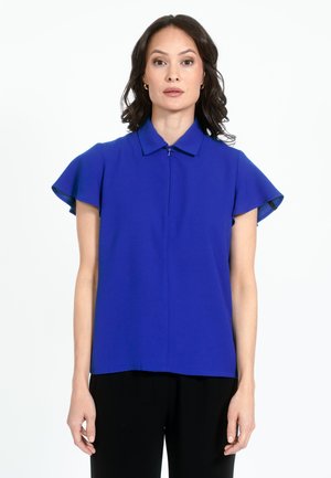 Modra kratka bluza s kratkimi rokavi, ovratnikom in zadrgo spredaj, z letečimi rokavi in gladko teksturo tkanine.