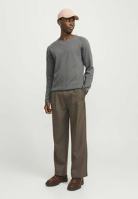 Gray long-sleeve sweater, loose brown trousers, and brown lace-up shoes. Light pink cap adds color. Plain texture, casual design.