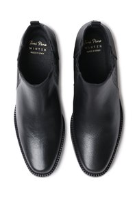 Scarpe in pelle nera con una silhouette elegante, finitura texturizzata, pannelli laterali elastici e una suola robusta. Etichettate "Toni Pons INVERNO, MADE IN SPAIN."