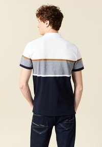 Pikétröja med vita, grå och marinblå horisontella ränder, med en brun accentband; korta ärmar; blandning av bomull, avslappnad passform.