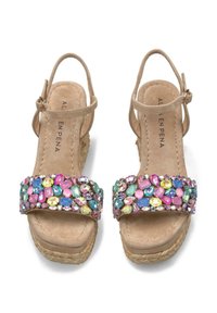 Beige wedge sandals with a textured fabric upper, featuring a colorful jeweled strap adorned with pink, blue, and yellow stones.