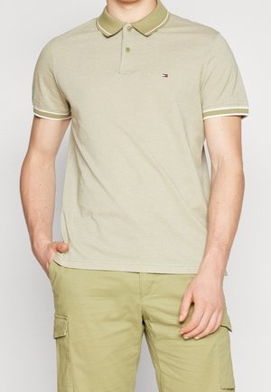 Lysegrøn polo med ribstrikket tekstur, to knapper og kontrasterende hvid kant ved krave og ærmer. Lille logo på brystet.