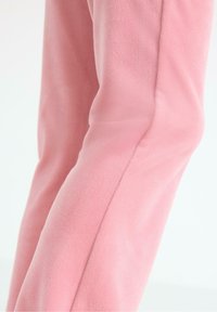 Fleecové kalhoty z měkké růžové tkaniny, s hladkou texturou, tapered designem a detaily na bočních švech.