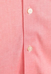 Roze geplooid overhemd met een gestructureerde stof en ronde, crème kleurige knopen. Bevat kleine witte stippen door het materiaal.