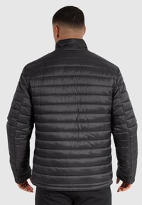 Veste matelassée noire avec coutures horizontales, col haut et texture lisse et brillante. Dotée de poignets élastiques et d'un design minimaliste.