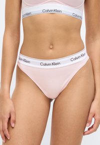 Ρόζ σλιπ μελάνζ με λευκή ελαστική μέση που φέρει μαύρη επωνυμία "Calvin Klein". Μαλακό ύφασμα και μίνιμαλ σχεδιασμός.