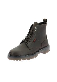Bottes chelsea en cuir marron avec une semelle en caoutchouc robuste, un laçage à l'avant et une languette sur le côté. Comprend des œillets en métal argenté et des coutures contrastantes.