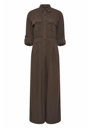 Combinaison marron foncé à manches longues avec fermeture boutonnée sur le devant, deux poches poitrine à rabat, manches retroussées avec pattes boutonnées et pantalon à jambes larges.
