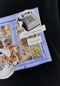 Graficzna kolaż przedstawiająca vintage telefon, ramę okna, pognieciony papier oraz odręczny tekst z czarnymi gwiazdkami na czarnym tle.