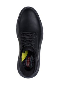Chaussures noires en cuir à enfiler avec surface texturée, bout rond et semelle en caoutchouc grise. L'intérieur présente une semelle intérieure jaune vif et une marque de résistance à l'eau.