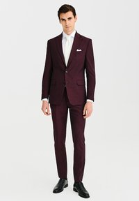 Burgundowy garnitur o dopasowanej sylwetce, jednozapinana marynarka, dwa guziki i klapy z wycięciem. Biała koszula i jedwabny krawat. Czarne buty eleganckie.