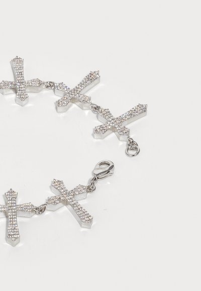 Hõbedane käevõru, kus on viis rhinestone'idega kaunistatud ristikut, mis on ühendatud väikeste rõngastega ja millel on homaariklamber, valgel taustal.
