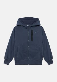 Casaco azul marinho com fecho éclair e capuz, forro em felpa, punhos elásticos, dois bolsos laterais e um bolso no peito com fecho de correr. Logotipo da Nike presente.