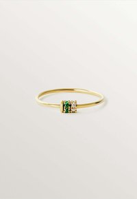 Anillo de oro con una banda delgada, que presenta un grupo de piedras verdes y blancas con acentos metálicos en un diseño simétrico.