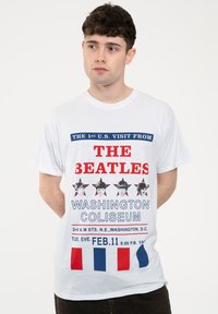 White cotton t-shirt featuring red and blue text, images of four individuals, and a star pattern; commemorates The Beatles' visit to Washington Coliseum.