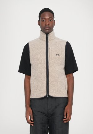 Ärmellose Weste für Herren aus hellgrauem Fleece, mit hohem Kragen, Frontreißverschluss und schwarzem Logo. Über einem schwarzen Kurzarmshirt getragen.