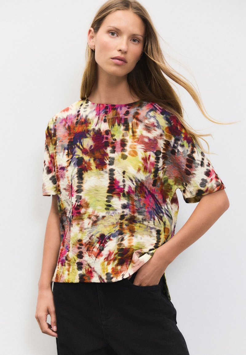 Blúzka s krátkymi rukávmi v viacfarebnom vzore tie-dye s odtieňmi ružovej, zelenej a čiernej, s okrúhlym výstrihom a voľným strihom.
