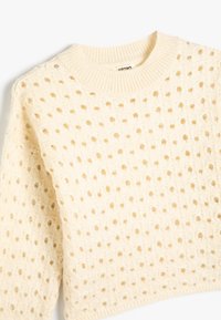 Maglione in crema con un motivo a trama aperta testurizzato, girocollo e polsini a costine, realizzato in un tessuto morbido e leggero.