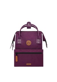 Purple canvas bag with a structured design, featuring a top handle, a front zip pocket, and a leather logo patch.