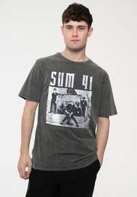 Gray cotton t-shirt with short sleeves and a round neckline, featuring a black and white graphic print of a band on the front.