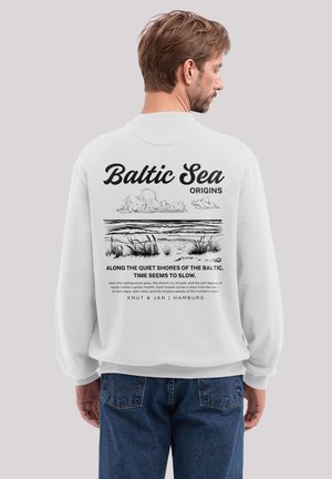 Weißer Sweatshirt mit einem grafischen Druck auf der Rückseite, der den Text "Ostsee", eine Landschaftsillustration und beschreibenden Text am unteren Rand zeigt.
