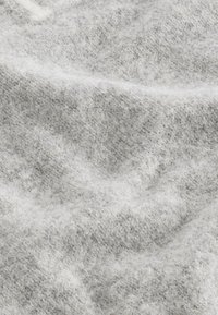 Tessuto grigio chiaro con trama, dall'aspetto morbido e lanuginoso, caratterizzato da tonalità variegate e un motivo sottile su tutta la superficie.