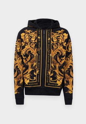 Czarna bluza z kapturem na zamek błyskawiczny z żółtymi i złotymi bogato zdobionymi barokowymi wzorami kwiatowymi oraz napisem "Versace Jeans Couture" wzdłuż zamka.