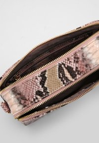 Bolso con estampado de serpiente en tonos rosa y beige, con un acabado texturizado, dos compartimentos con cremalleras en tono dorado y forro suave.