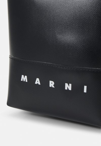 Sac à main noir texturé avec le lettrage blanc "MARNI" en bas, présentant un design rectangulaire élégant et une finition lisse.