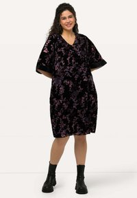 Musta samettimekko, jossa on violetteja ja sinisiä kukkakuoseja, lyhyet hihat ja V-pääntie. Yhdistettynä mustiin nilkkasaappaisiin.