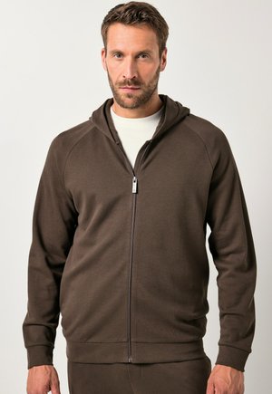 Sudadera con cremallera marrón hecha de un tejido suave y texturizado. Presenta capucha, mangas raglán y puños de canalé. Destaca el detalle de la cremallera plateada.