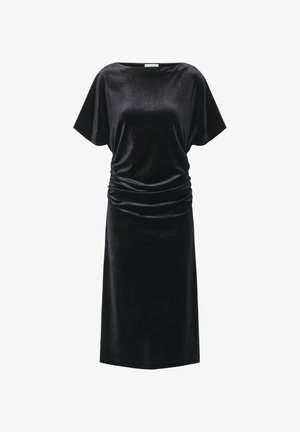 Zwarte fluwelen jurk met een losse pasvorm, kapmouwen en gatherdetails aan één zijde. Middenlange jurk, gladde textuur, eenvoudig ontwerp.