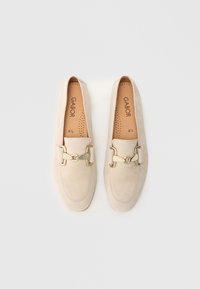 Beige suede loafers featuring a gold metal buckle accent, rounded toe, and perforated insole design. Size 4½.