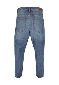 Jean en denim bleu vu de dos avec deux poches arrière, passants de ceinture, et un patch en cuir marron sur la taille.