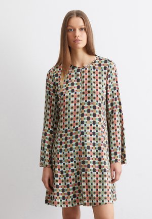 Langomslang jurk van lichtgewicht stof met een geometrisch patroon van vierkanten en cirkels in gedempte kleuren op een lichte achtergrond.