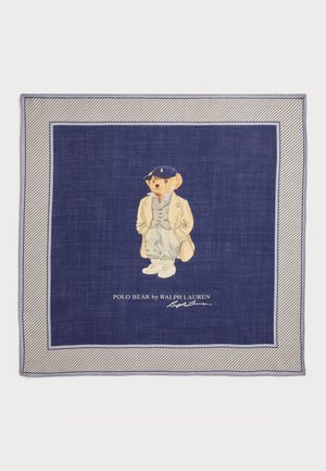 Marineblaue scarf mit einem Cartoon-Bären in einem beigen Mantel und einer Mütze, der weiße Sneaker trägt, umrandet von einem schmalen Streifenmuster. Darunter steht der Text "POLO BEAR by RALPH LAUREN."
