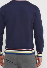 Mörkblå sweatshirt med rund nacke, prydd med flerfärgade randiga ärmslut och nederkant. Slät textur, långa ärmar och en figurnära silhuett.