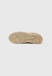 Σόλα αθλητικού παπουτσιού ανοιχτού καφέ με υφή από καουτσούκ για καλύτερη πρόσφυση, με κυκλικό σχέδιο και το λογότυπο της μάρκας στο κέντρο.