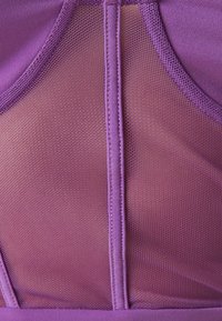 Top atletico viola con design a pannello in rete, texture del tessuto liscia e dettagli delle cuciture rinforzate, che offre una vestibilità traspirante.