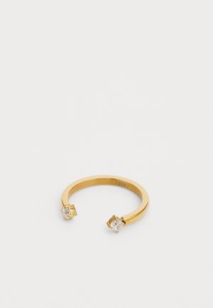 Kultakuvioinen metallirengas, jossa on säädettävä avoin muotoilu ja joissa kummassakin päässä on kirkas, pyöreä keinokivimäinen kivi. Tasainen, kiillotettu pinta.