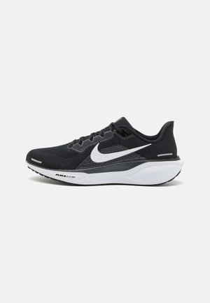 Chaussure de running Nike noire avec logo swoosh blanc, semelle intermédiaire blanche et semelle extérieure noire, vue de l'intérieur.