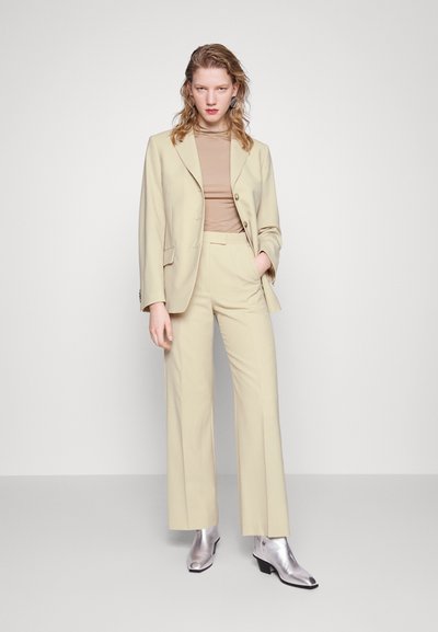 Beige tailored blazer with matching wide-leg trousers, paired with a brown top and silver ankle boots. Smooth fabric with structured design.